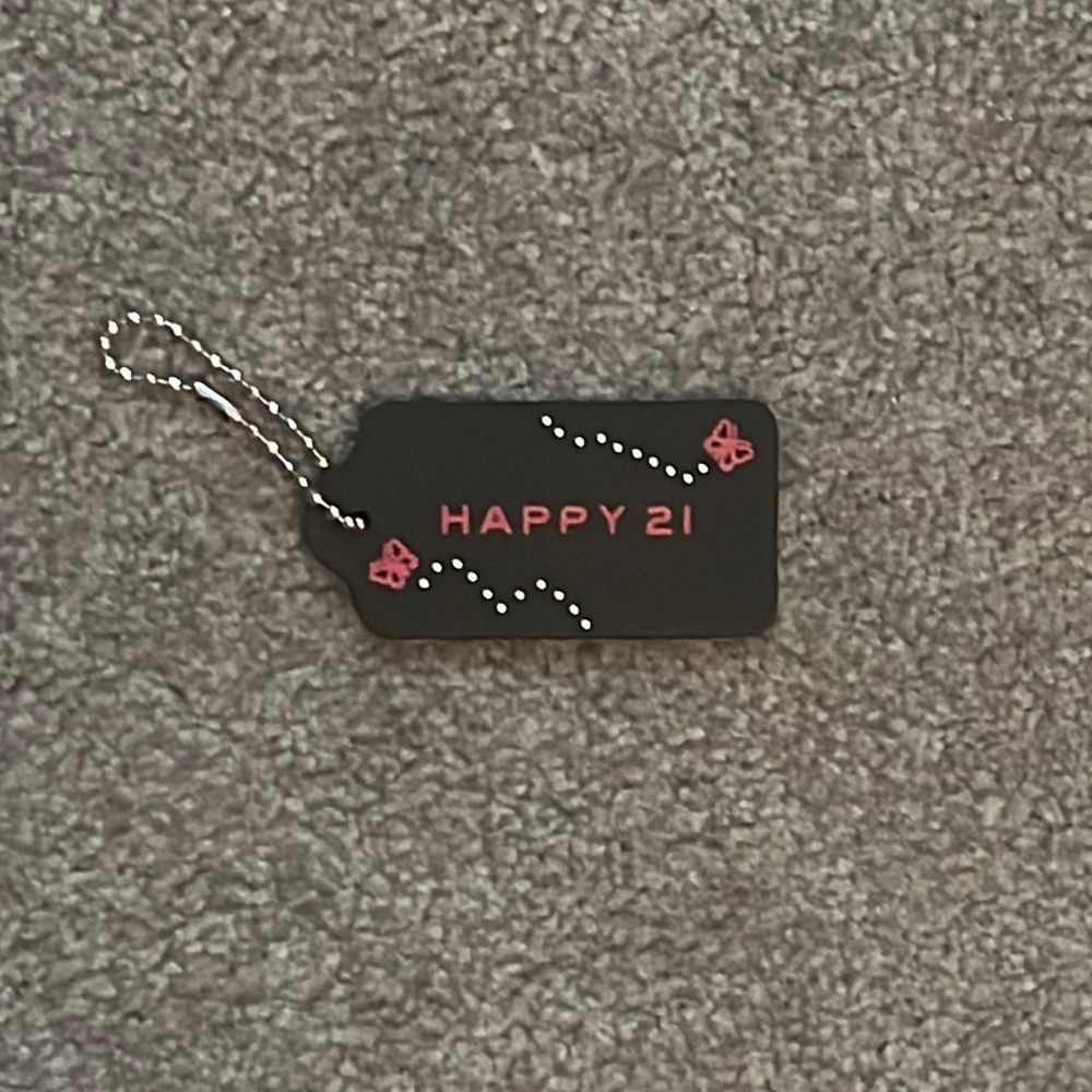Coach bag chain with pink butterflies and inscribed with “Happy 21st”